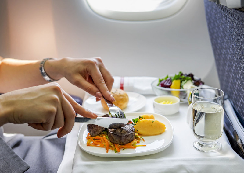 Fly Gluten-Free With These Airlines_Woman-eating-steak-on-an-airplane