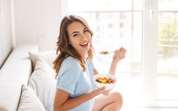 Cheerful,Young,Woman,Eating,Healthy,Breakfast,While,Sitting,On,A